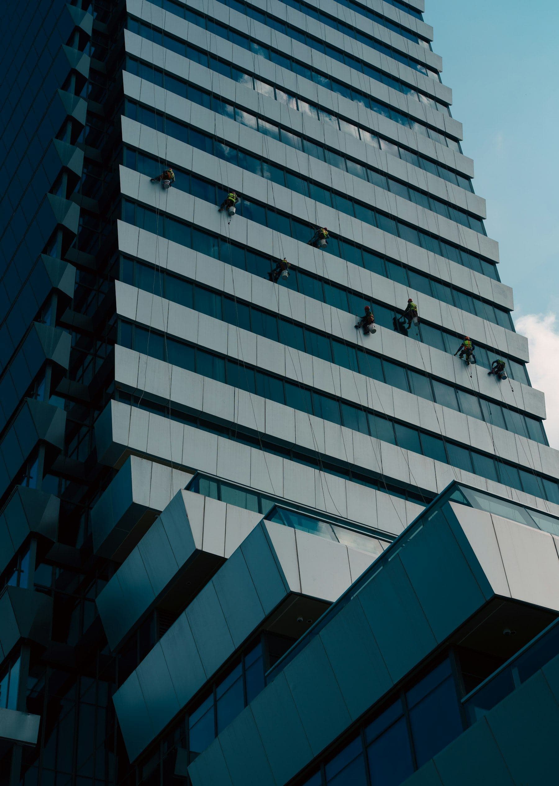 Rope-access technicians on a blue glass tower